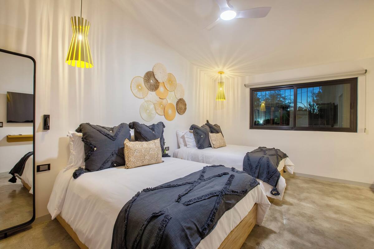 Un dormitorio moderno con dos camas, un espejo grande y decoración mural.