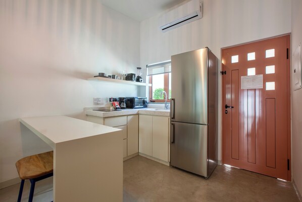 A compact kitchen with a refrigerator, a coffee maker, and a window. - Quinta Lolita (La Paz)