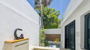 Un espace extérieur moderne avec une petite piscine, une statue, une chaise jaune et un mur en briques.