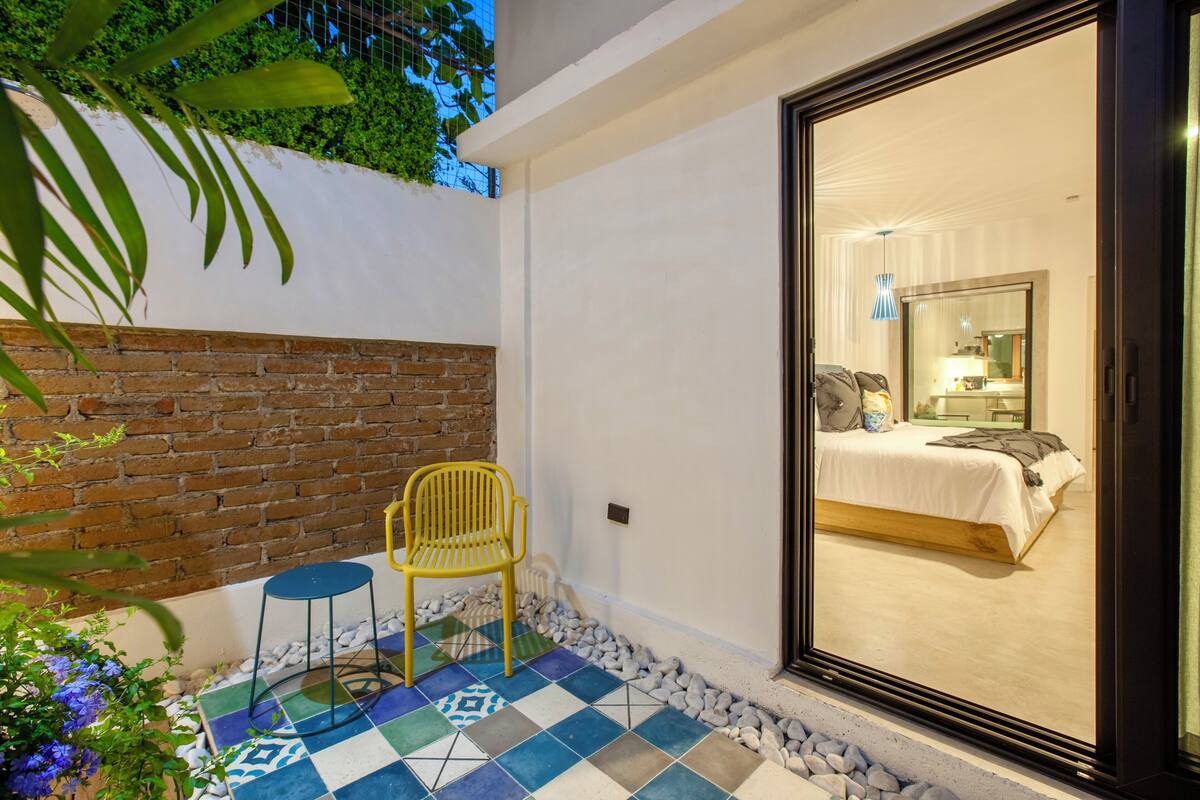 Una habitación con cama, una silla y vistas a través de un ventanal.