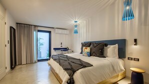Une chambre moderne avec un grand lit, une table de chevet, une suspension bleue et une vue à travers une porte vitrée.
