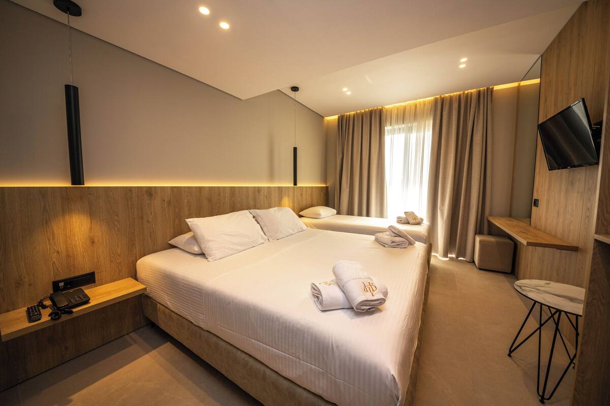 Une chambre d’hôtel moderne, dotée d’un grand lit, de tables de chevet, d’un bureau et d’une télévision.