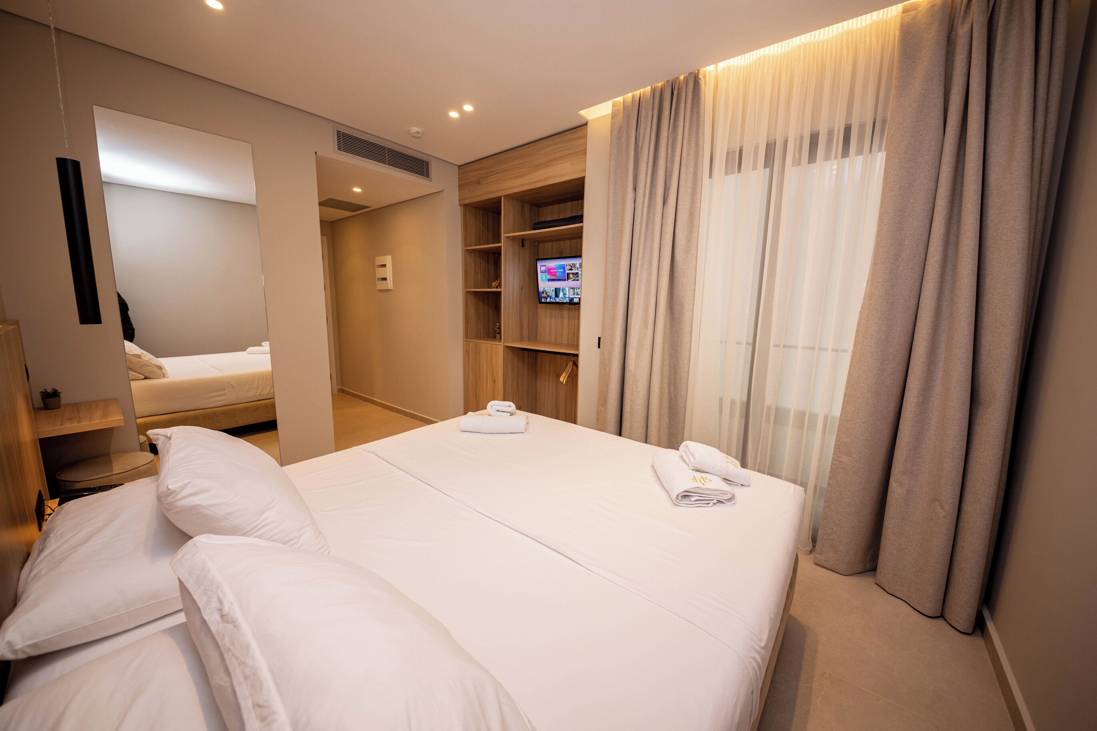 Una habitación de hotel con una cama grande, televisión, armario y zona de baño.