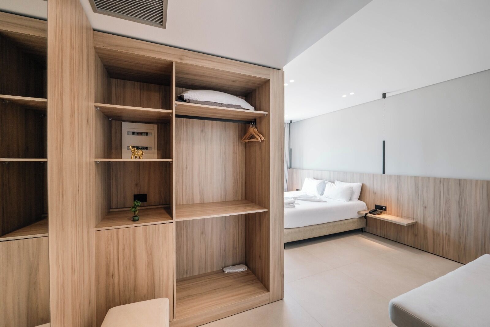 Un dormitorio moderno con armario empotrado, cama con ropa blanca y una mesita de noche pequeña.