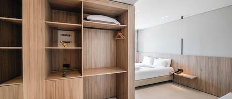 Un dormitorio moderno con armario empotrado, cama con ropa blanca y una mesita de noche pequeña.