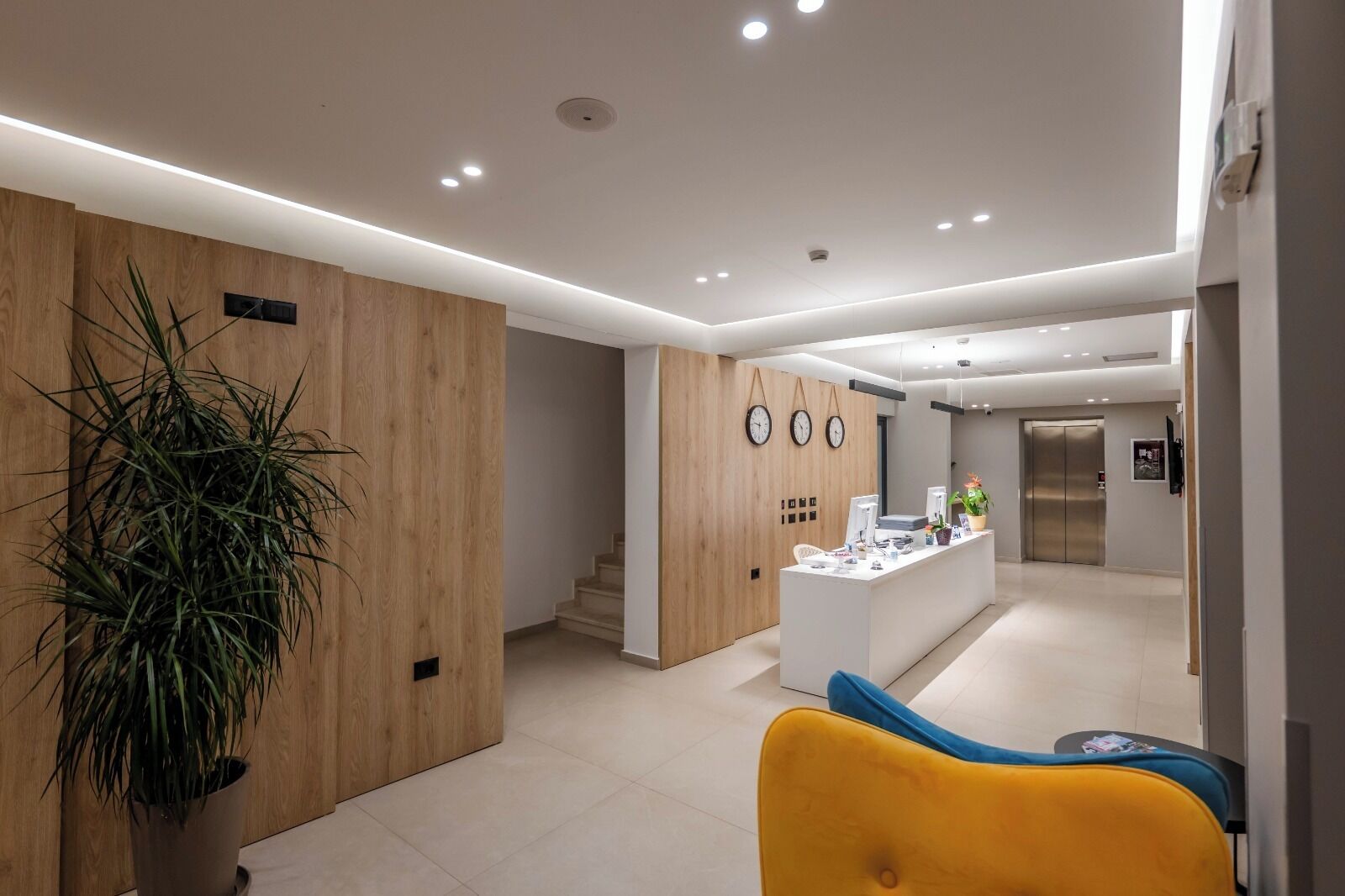 A modern reception area with a wooden accent wall, a reception desk, and a staircase leading to another floor.