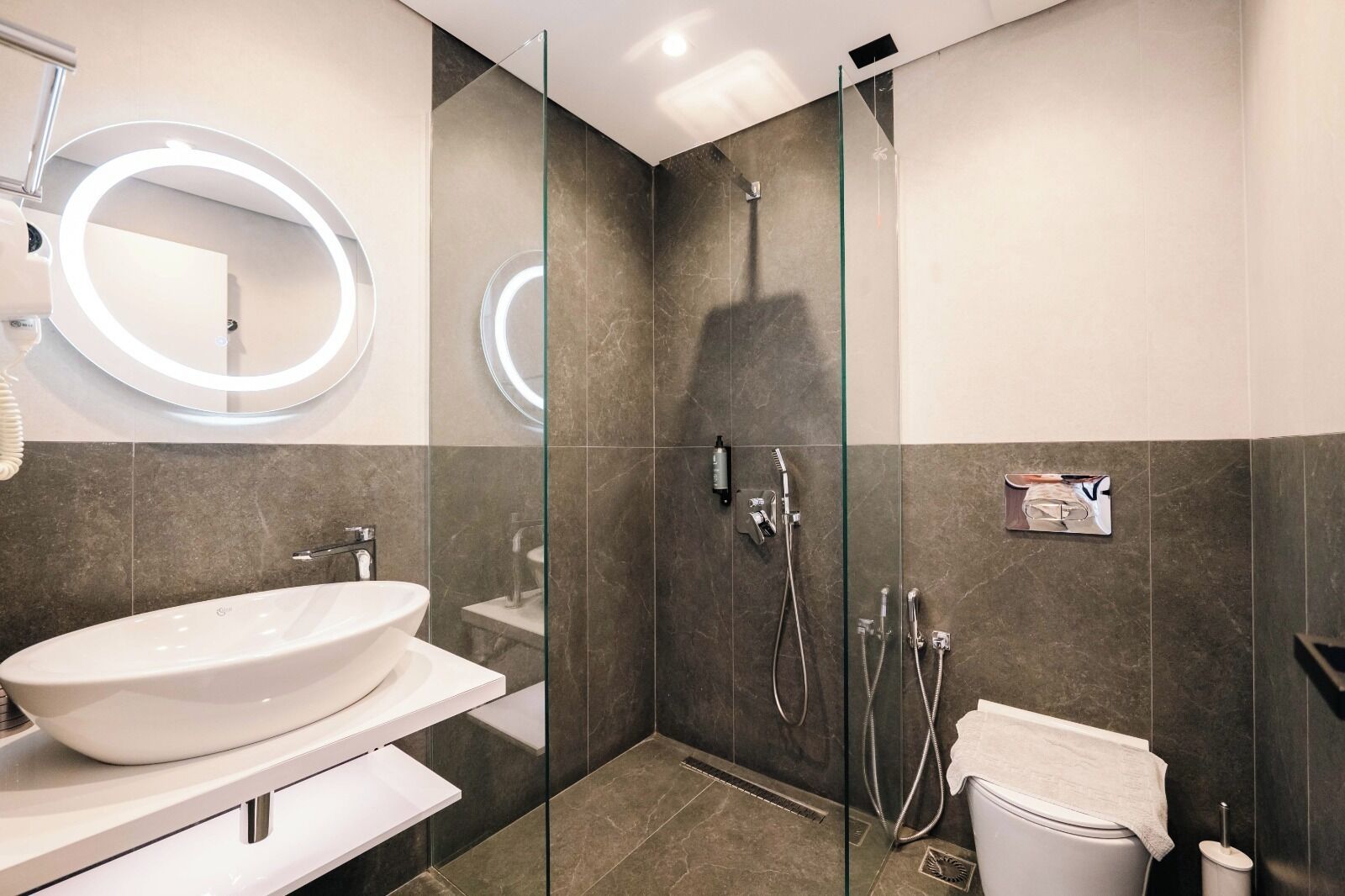 A modern bathroom with a large oval sink, a glass-enclosed shower, and a toilet.