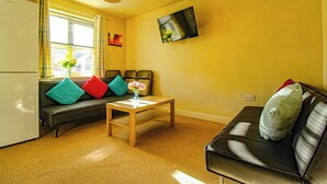 Ein Wohnzimmer mit einer Couch, einem Couchtisch und einem an der Wand befestigten Fernseher.