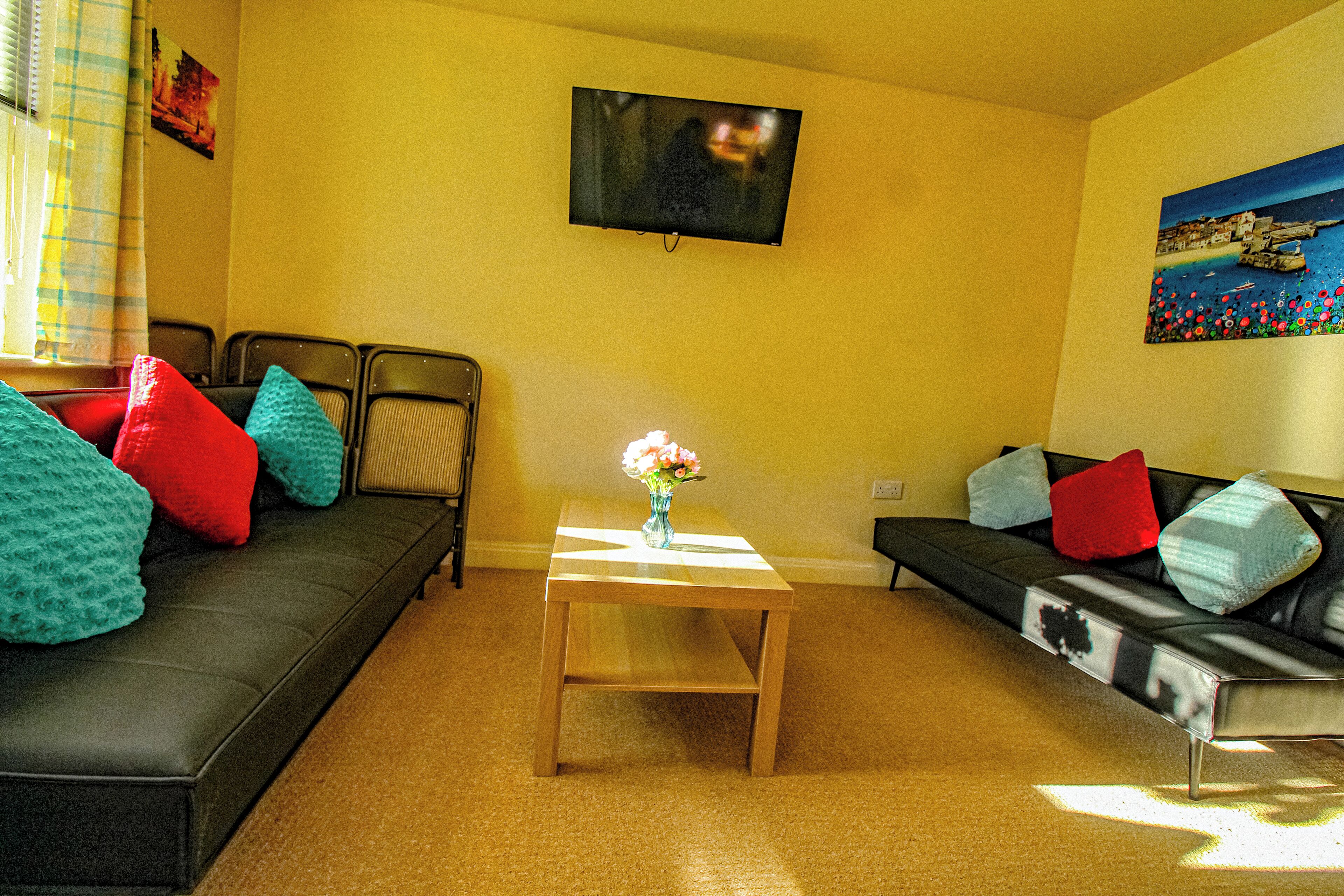 A living room with two sofas, a coffee table, and a TV mounted on the wall.