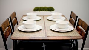 A dining table with four white bowls and plates, surrounded by wooden chairs.