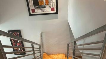 A staircase with wooden steps and metal railings, leading to a landing with a framed abstract painting.