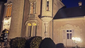 A historic building with a turret, large windows, and a well-lit entrance. - Le Château de Leugny (Plaine-et-Vallées)