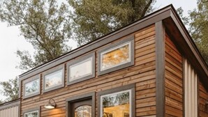 Una cabaña de madera con una fogata, asientos exteriores y una escalera que lleva a la entrada.