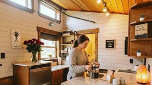 Una cocina con una mujer preparando café, una estufa a gas, un refrigerador y un techo de madera.