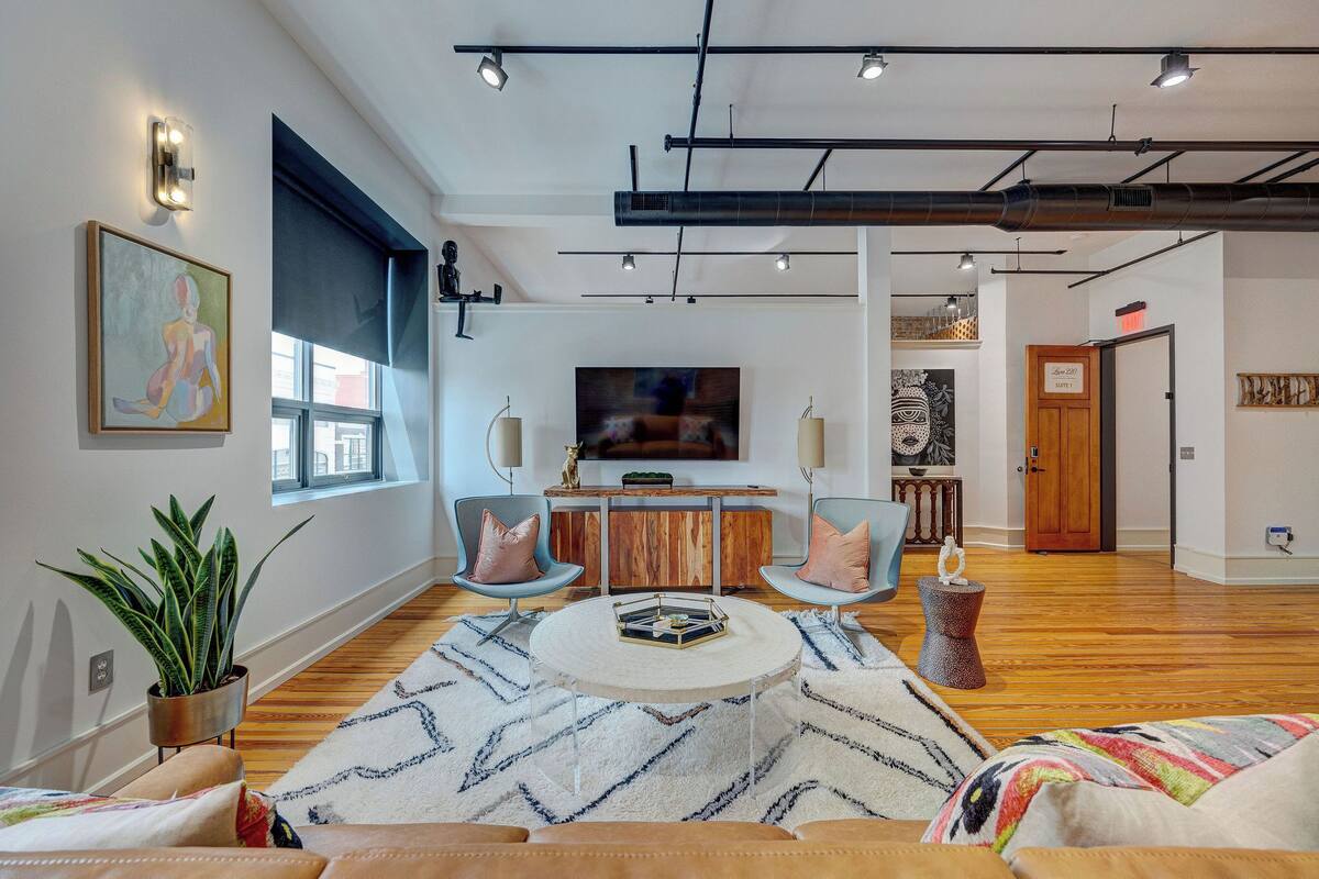 Una sala de estar moderna con un televisor grande, piso de madera y una mesa de centro.