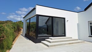 Una casa moderna con amplios ventanales, un camino de hormigón y fachada blanca.