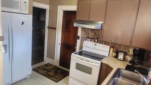 Une cuisine compacte équipée d’un réfrigérateur, d’une cuisinière, d’un four à micro-ondes et d’un évier.