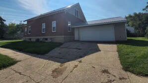Une maison à deux étages, construite en briques, avec un garage, une allée et une pelouse.