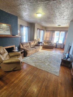 A living room with a sectional sofa, a recliner, a coffee table, a fireplace, and a television.