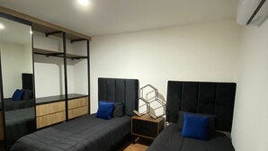 Ein Zimmer mit zwei Betten, Holzboden, einem großen Spiegel und einer Klimaanlage.