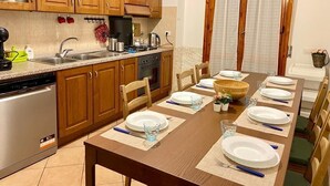 A kitchen with wooden cabinets, a dishwasher, and a dining table set for six with plates, glasses, and cutlery.