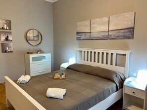 A neatly arranged bedroom with a bed, bedside tables, a dresser, and wall art. - CAMILLA FLORENCE APARTMENT (Firenze)