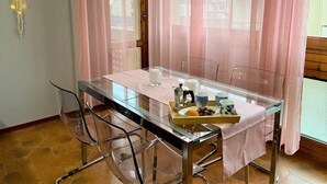 A dining area with a glass table, chairs, and a tray with food and drinks.