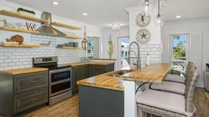 A modern kitchen with wooden countertops, stainless steel appliances, and a central island with seating. - Coral Cove (Fort Myers Beach)