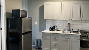 Une cuisine moderne avec des meubles gris, des appareils en acier inoxydable et un dosseret carrelé.