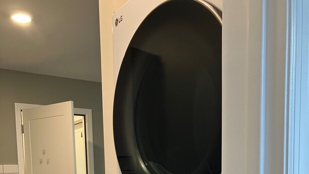 Une buanderie équipée d’un lave-linge et d’un sèche-linge à chargement frontal, d’une porte donnant sur une autre pièce et d’un mur recouvert de carreaux.