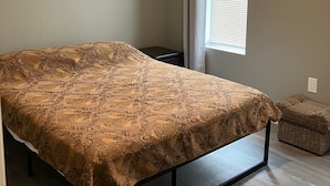 Une chambre à coucher avec un lit, une fenêtre avec des rideaux, une table de chevet et un appareil de climatisation.