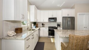 A modern kitchen with white cabinets, stainless steel appliances, and a marble countertop. - Holiday Everyday (Fort Myers Beach)