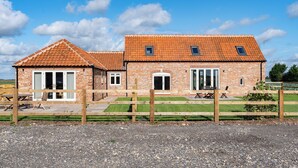 A brick building with a tiled roof, a wooden fence, and a gravel driveway.