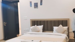 A modern bedroom with a large bed, a ceiling fan, and a door. - Global luxary stay  (Gurugram)