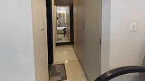 A narrow hallway with a bed and a bathroom visible in the distance. - Global luxary stay  (Gurugram)