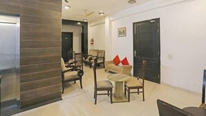 A spacious living area with multiple seating options, including sofas and chairs, arranged around a central coffee table. - Global luxary stay  (Gurugram)