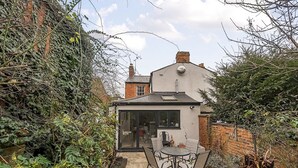 Ein kleines Haus mit Glastür und Terrassenausgang, inklusive Tisch und Stühlen.