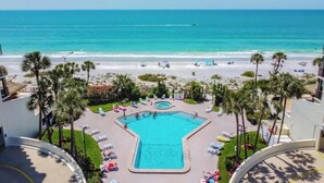 A resort with a swimming pool, beach, and palm trees.