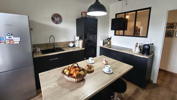 A modern kitchen with a refrigerator, sink, and wooden countertop. There is a basket of fruit on the table and a coffee maker on the counter. - Charming T3 with balconies in Ajaccio (Ajaccio)