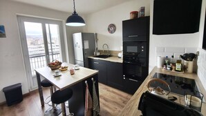 A modern kitchen with a dining area, a black refrigerator, an oven, and a coffee machine. - Charming T3 with balconies in Ajaccio (Ajaccio)