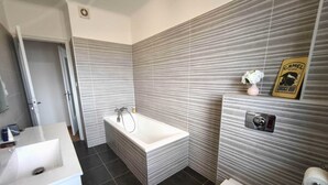 A bathroom with a bathtub, toilet, and sink. - Charming T3 with balconies in Ajaccio (Ajaccio)