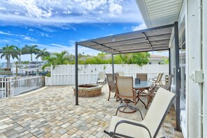 A covered patio with a fire pit, outdoor furniture, and a view of the ocean. - Villa At Bahia Shores-whole Property (St. Pete Beach)