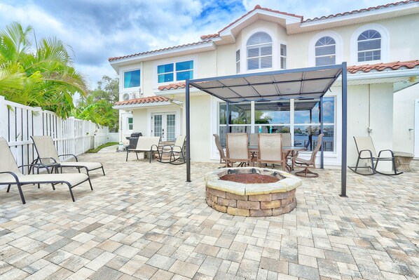 A patio area with a fire pit, outdoor furniture, and a covered seating area. - Villa At Bahia Shores-whole Property (St. Pete Beach)