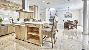 A spacious kitchen with a central island, wooden cabinets, and a dining area with a chandelier.