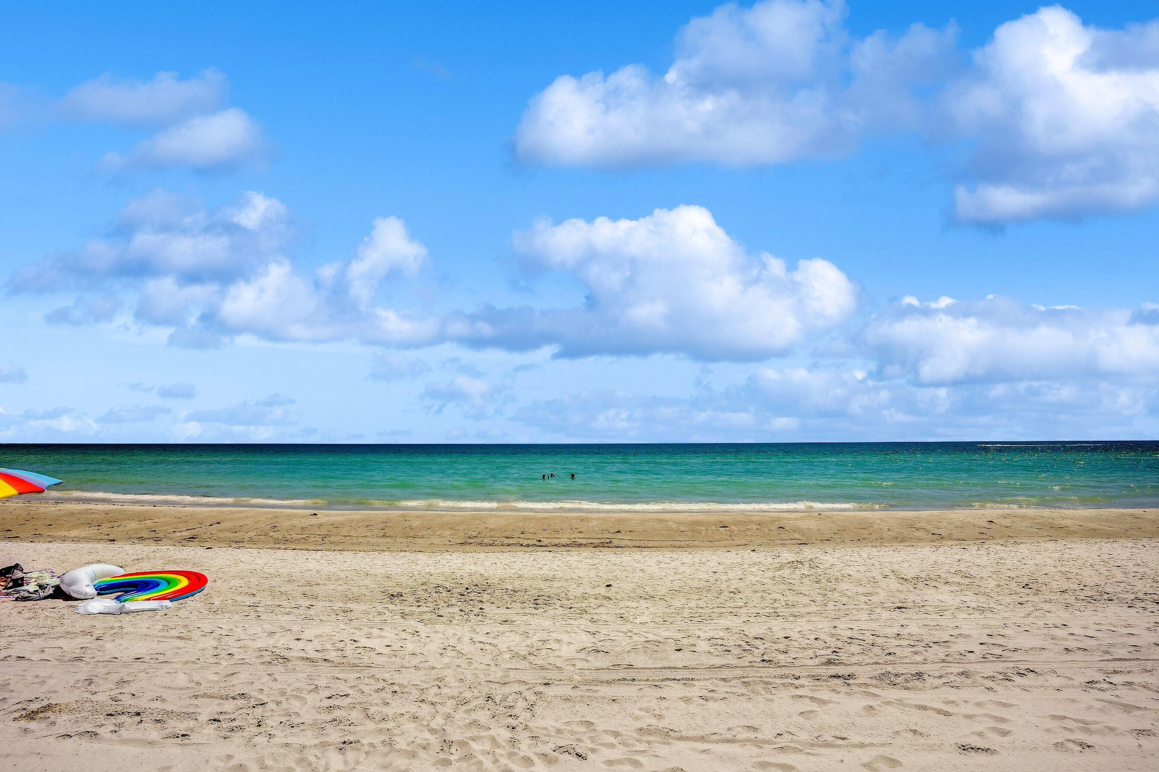 Ein Strand mit blauem Himmel und ruhigem Wasser.