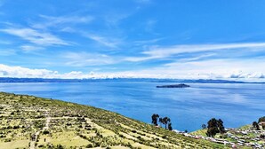 A coastal landscape with a clear view of the sea, a small island, and a hilly terrain with sparse vegetation. - Kalluchi Ecolodge (La Paz)