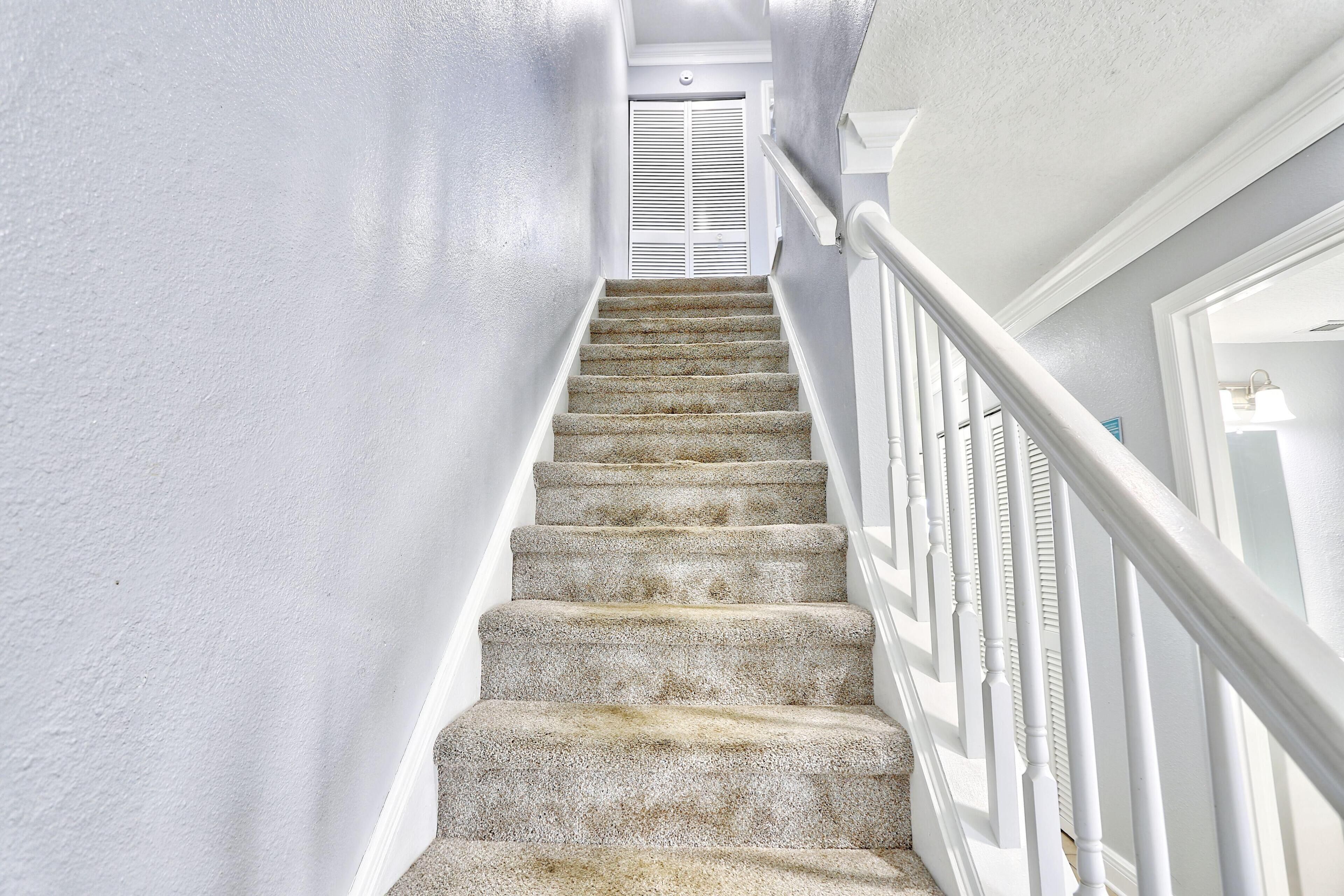 Una escalera con barandas blancas y una puerta blanca al final.