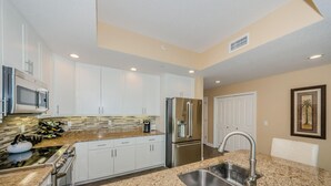 A modern kitchen with white cabinets, stainless steel appliances, granite countertops, and a built-in microwave. - Dolphin Key 504 - Premier (Indian Shores)
