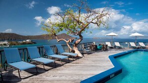 A poolside area with lounge chairs, a tree, and a view of the sea. - NEWLY RENOVATED! 1BR/1BA Beautiful Condo @Point Pleasant/Great views/3 Pools! (St Thomas)