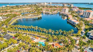 Luftaufnahme eines Resorts mit einem zentralen Wasserspiegel, umgeben von Palmen und Gebäuden mit roten Dächern.